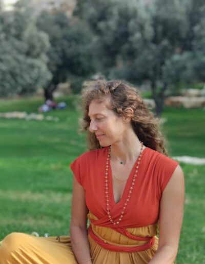Alit looking pensively to the side, trees in the background