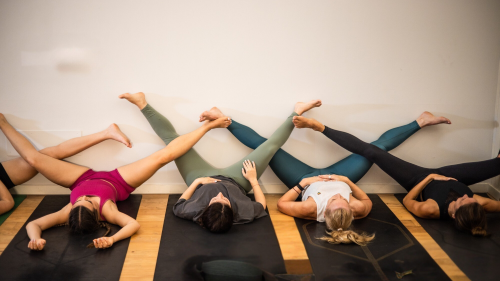 trainees in a yoga teacher training, lying down legs up the wall