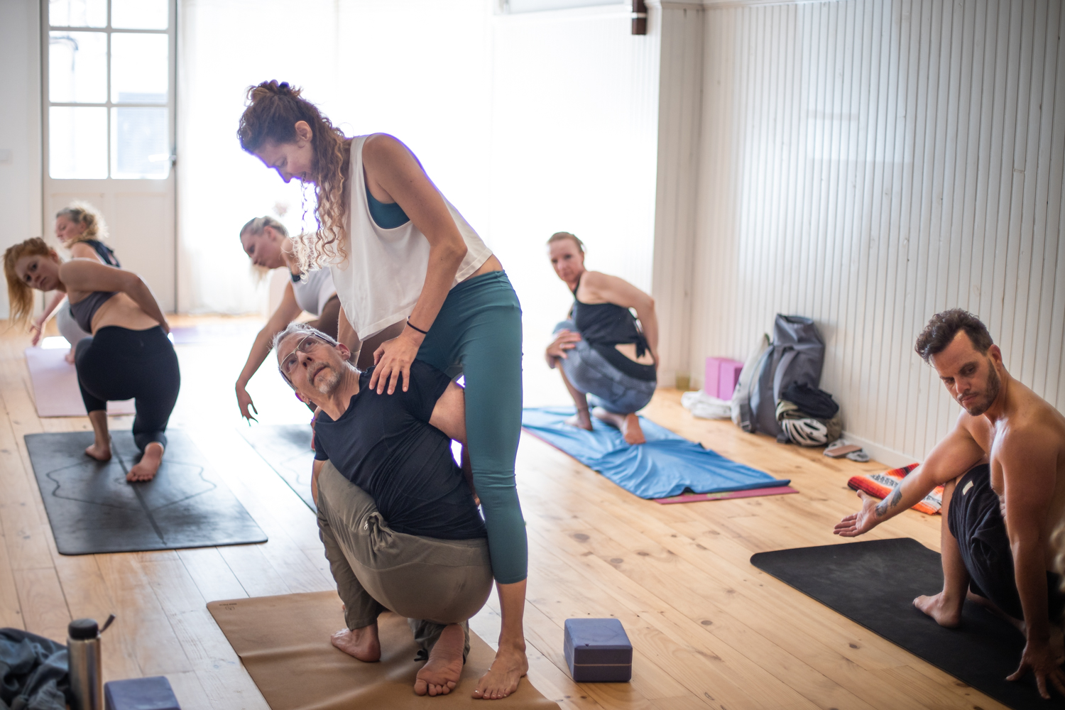 1T9A5366 yoga teacher assist a student in a seated twisting posture