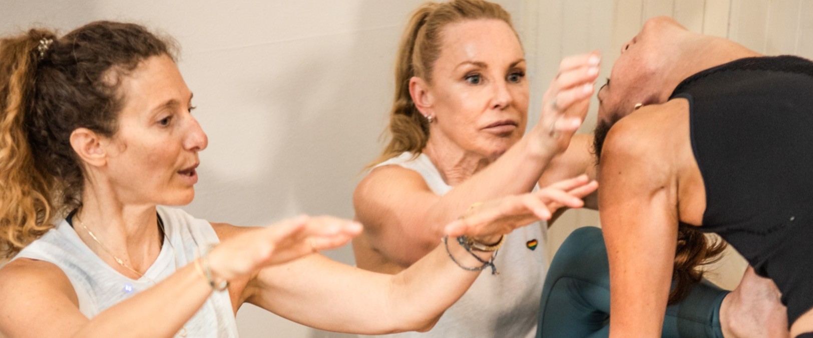 yoga teacher sitting and showing trainees how to assist another trainee with touch